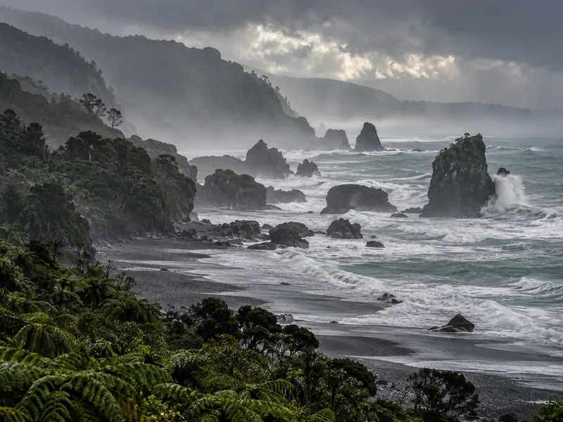 Wild West Coast beach with driftwood and dramatic clouds